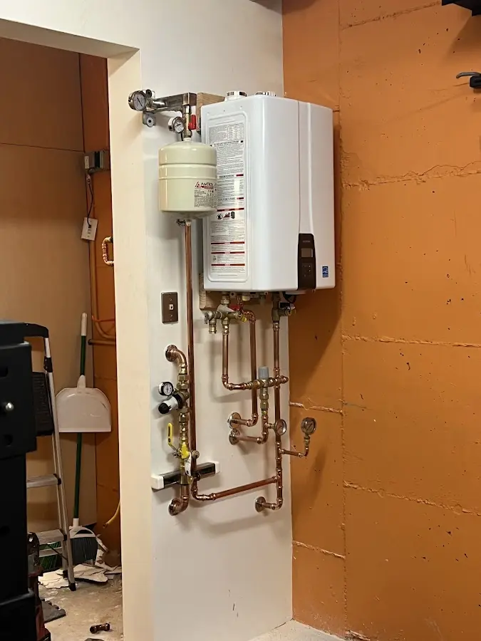 Plumbing technician inspecting water heater connections in Bystrom